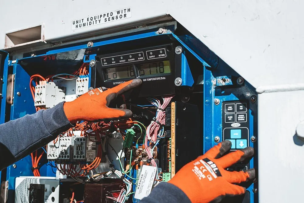 Técnico interviniendo el panel de control eléctrico de una unidad reefer